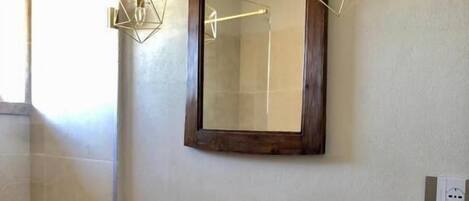 A bathroom with a large mirror, a white sink, and a wooden vanity.