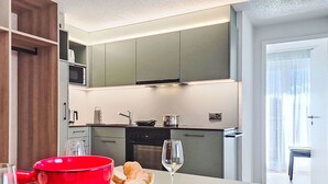 Eine moderne Küche mit Essbereich, mit einem roten Topf, einem Glas, einem Teller mit einem Messer und einem Korb mit Brot.
