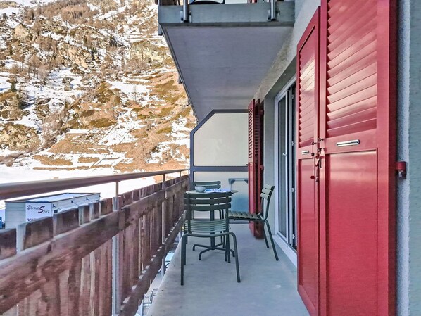 A balcony with a table and chairs, overlooking a snowy mountain. - Nice apartment for 4 guests with WIFI, TV and balcony (Zermatt)