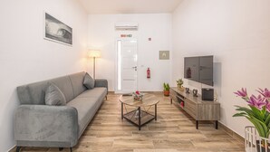 Una sala de estar moderna con un sofá gris, una mesa de centro, un televisor y una planta en maceta.