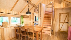 A wooden interior with a dining area, a staircase, and a clock on the wall. - Boshuis Dorus met sauna | park d`n Mastendol (Rijen)