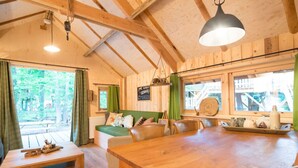 A cozy cabin interior with a wooden dining table, a sofa, and a bench. - Boshuis Dorus met sauna | park d`n Mastendol (Rijen)