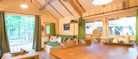 A cozy cabin interior with a wooden dining table, a sofa, and a bench.