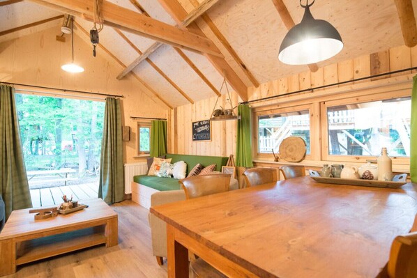 Interior acogedor de una cabaña con una mesa de comedor de madera, un sofá y una banca.