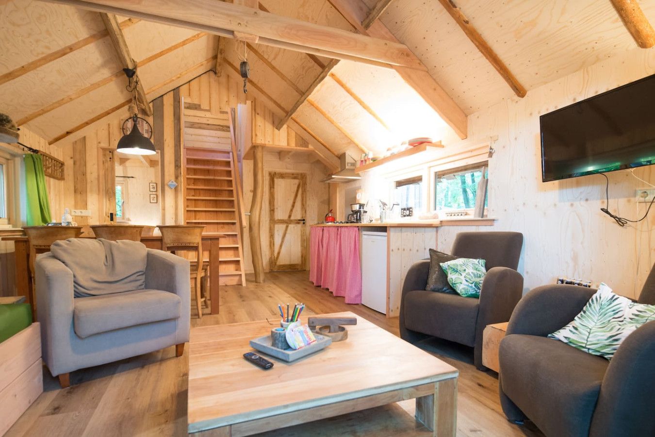 A cozy wooden cabin interior with a dining area, kitchen, and seating space.
