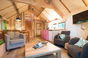 Interior acogedor de una cabaña de madera con comedor, cocina y zona de estar.