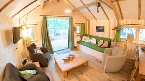 A cozy wooden cabin interior with a sofa, chairs, a coffee table, and a dining table. - Boshuis Dorus met sauna | park d`n Mastendol (Rijen)