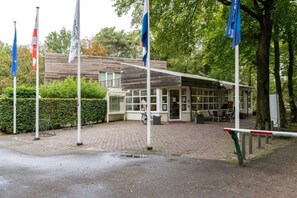 A building with a covered entrance, flags, and a paved area in front.