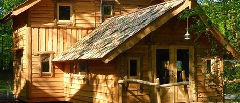 A wooden cabin with a porch, a small window, and a door.