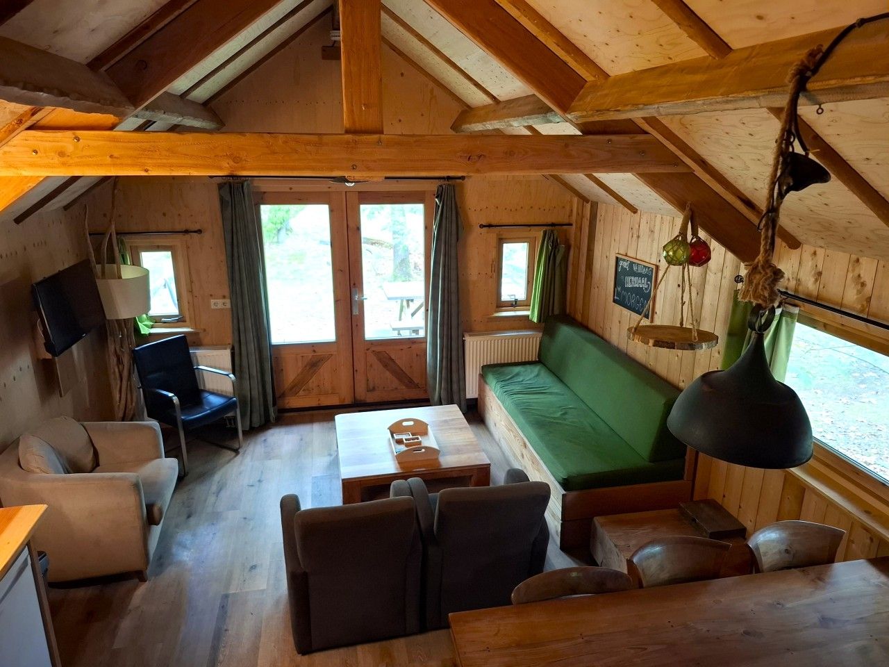 L'intérieur d'une cabine comprenant un canapé, des fauteuils, une table et un téléviseur.