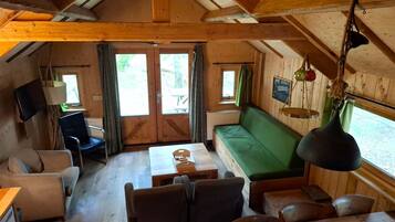 L'intérieur d'une cabine comprenant un canapé, des fauteuils, une table et un téléviseur.