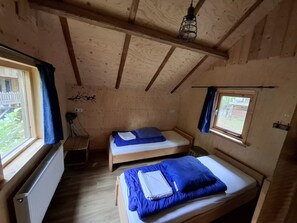 Una habitación pequeña y acogedora con dos camas de madera, un radiador y una ventana con cortinas.
