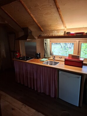 Una cocina compacta con mostrador de madera, un lavamanos, lavavajillas y ventana con vistas a zonas verdes.