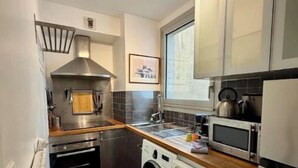 A compact kitchen with a washing machine, oven, microwave, and a window above the sink. - NEW! "Le Débarcadère" 4P near Palais Congrès (Paris)