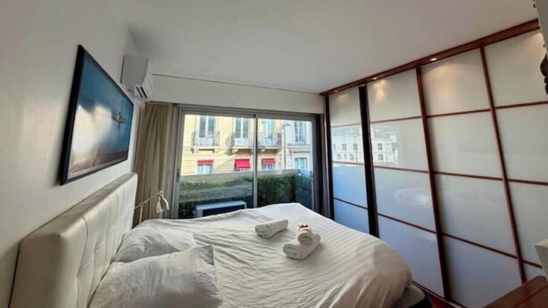 A hotel room with a large bed, a view of buildings through the window, and a sliding door with a traditional design. - NEW! "Le Débarcadère" 4P near Palais Congrès (Paris)