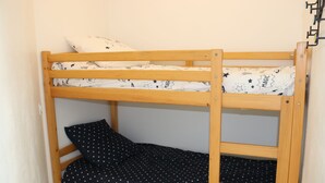 Ein Stockbett mit einer Matratze in Weiß und Schwarz sowie einem Holzrahmen und einem Kopfkissen mit Sternenmuster.