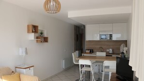 Eine moderne Küche mit weißen Schränken, einer Mikrowelle und einem Essbereich mit Tisch und Stühlen.