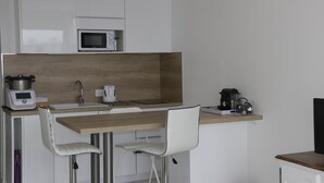 Eine kleine Küche mit Mikrowelle, Kaffeemaschine und einer Holzarbeitsplatte.