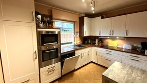 Cozinha moderna com armários brancos, eletrodomésticos de aço inoxidável e piso de madeira em padrão herringbone.