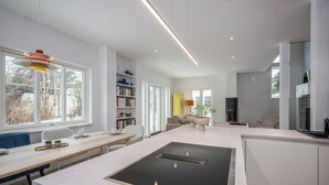 Une cuisine moderne dotée d’une cuisinière intégrée, d’un coin repas avec un banc et une table, et d’une bibliothèque.