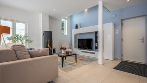 Un salon moderne avec un canapé beige, une table basse en verre, une cheminée et un téléviseur.
