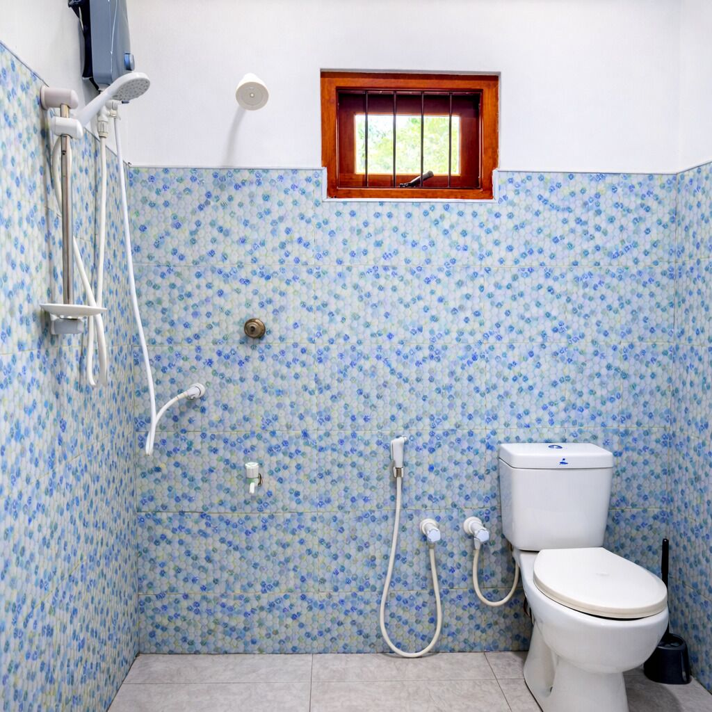 A bathroom with a toilet, shower, and window.