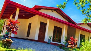 A house with a red roof, white walls, and a covered porch with potted plants. - Wilpattu Gagana Guest  (Pahala Maragahawewa)
