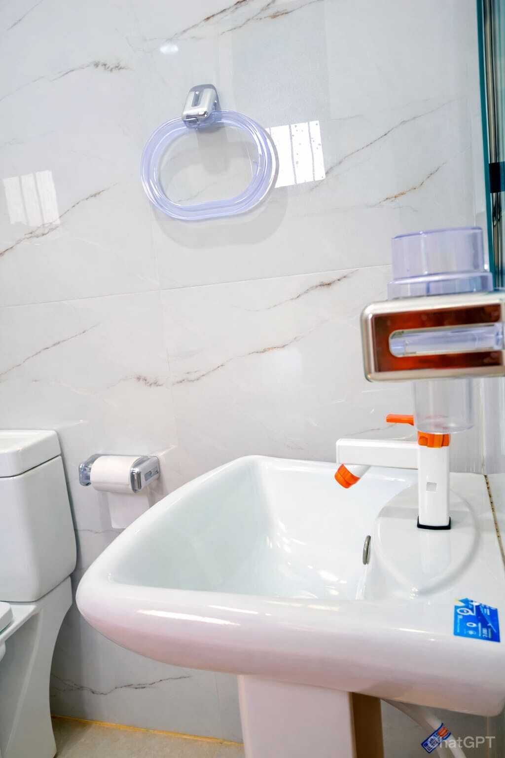 A bathroom with a white sink, a toilet, and a marble wall.