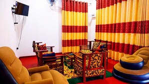 A room with a sofa, a small table, and a patterned chair. - Wilpattu Gagana Guest  (Pahala Maragahawewa)