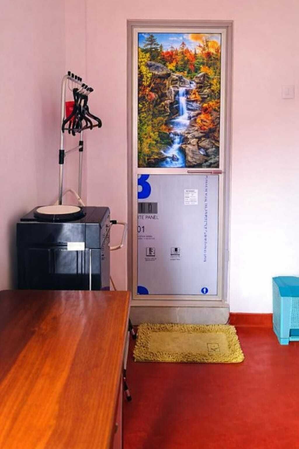 Una habitación con una mesa de madera, un cuadro enmarcado de una cascada, un armario negro y una silla azul.