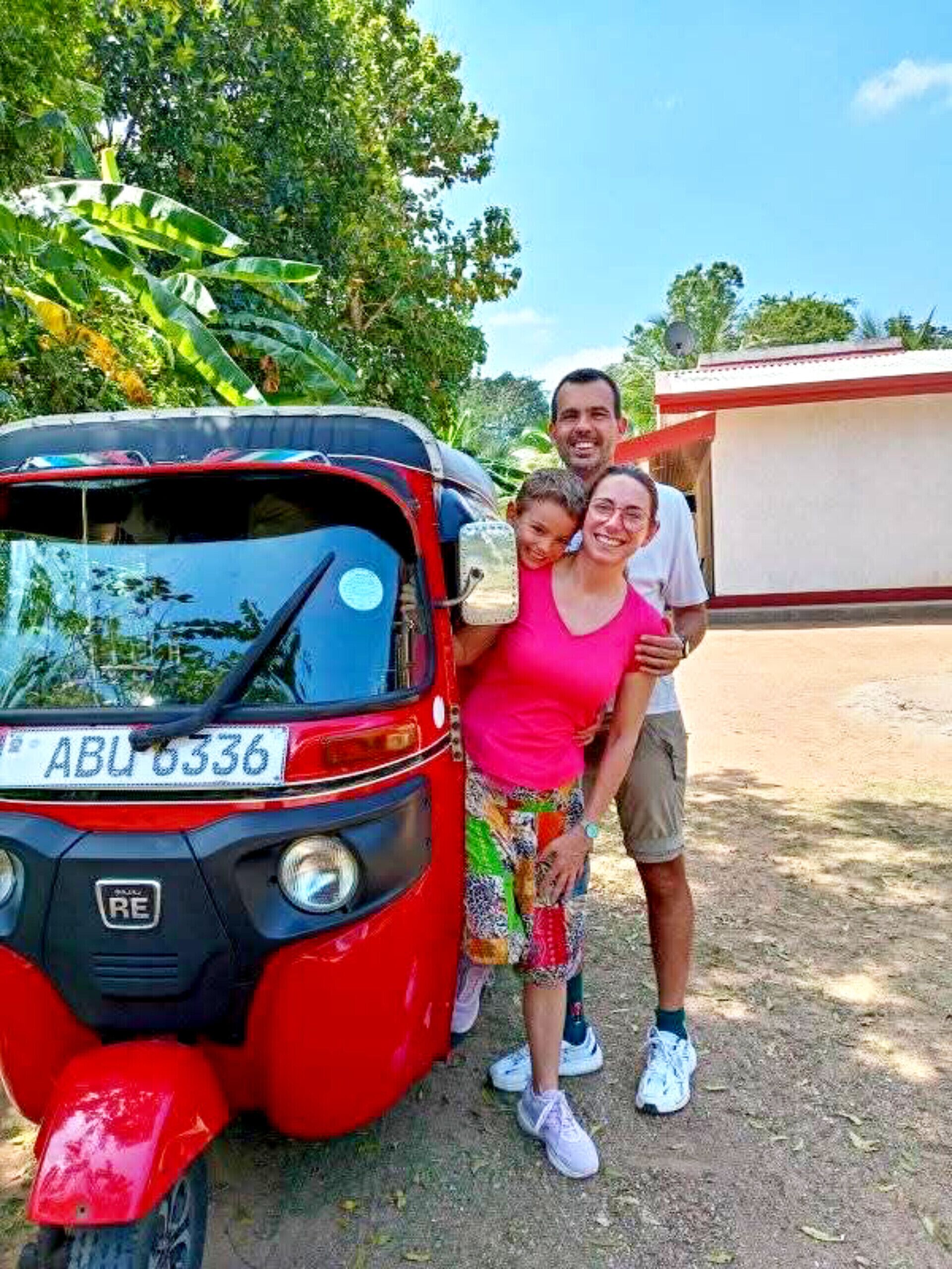 A red auto-rickshaw parked outdoors with a license plate visible.