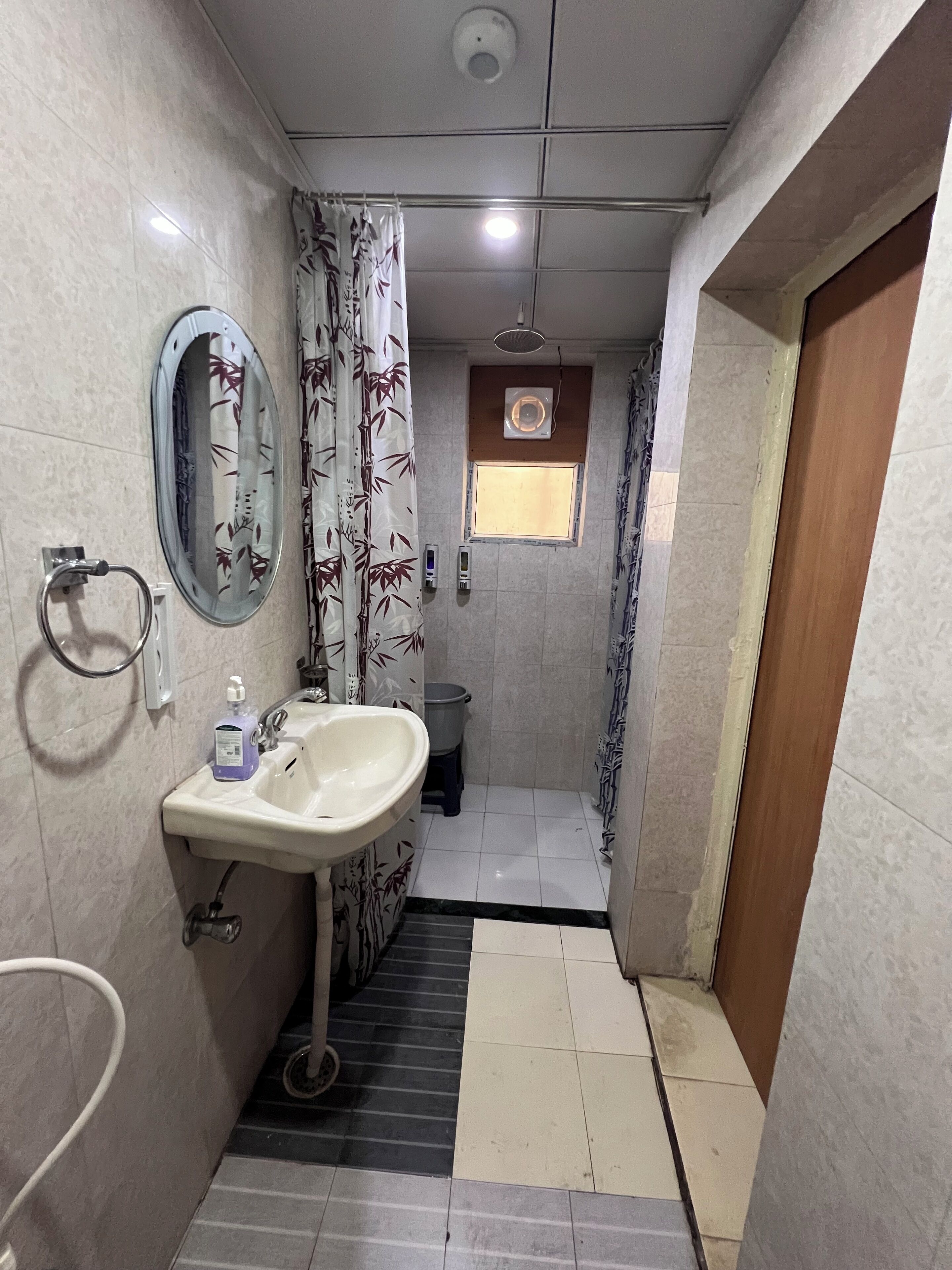 A compact bathroom with a sink, mirror, toilet, and shower area.