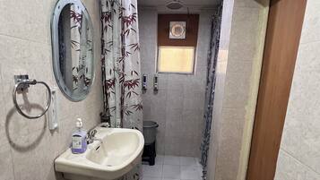 Un baño pequeño con lavamanos, espejo, inodoro y zona de ducha.