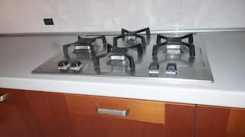 Una cocina con estufa a gas, encimera blanca y armarios de madera.