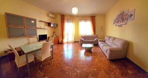 A living room with a dining area, a sofa, a TV, and a coffee table. - San Francesco Apartment (Bracciano)