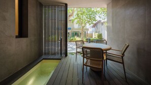 A modern interior with a wooden table and chairs, a small water feature, and a view of the street outside. - Evangelisti Palace (Bellaria-Igea Marina)
