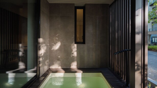 A modern spa area with a large bathtub, a wooden bench, and a glass wall. - Evangelisti Palace (Bellaria-Igea Marina)