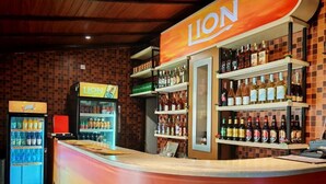 A bar area with a counter, shelves of liquor bottles, and a refrigerated beverage dispenser. - Lake Reach Hotel (Kandy)