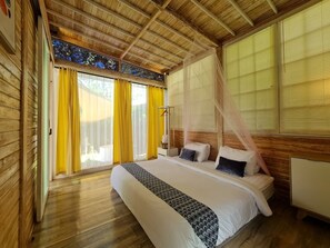 Quarto com teto de madeira, cama com roupa de cama branca, cortinas amarelas e janela com vista.