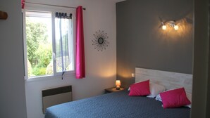 A bedroom with a bed, a nightstand with a lamp, a window with curtains, and a wall-mounted light fixture. - Gite Casteddu 2 with heated pool for lovers of peace and nature (San Gavino di Carbini)