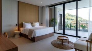 A modern bedroom with a large bed, a round coffee table, and a view of the outdoors. - Diamond Hill 10 Br Heated Pool (Bandung)