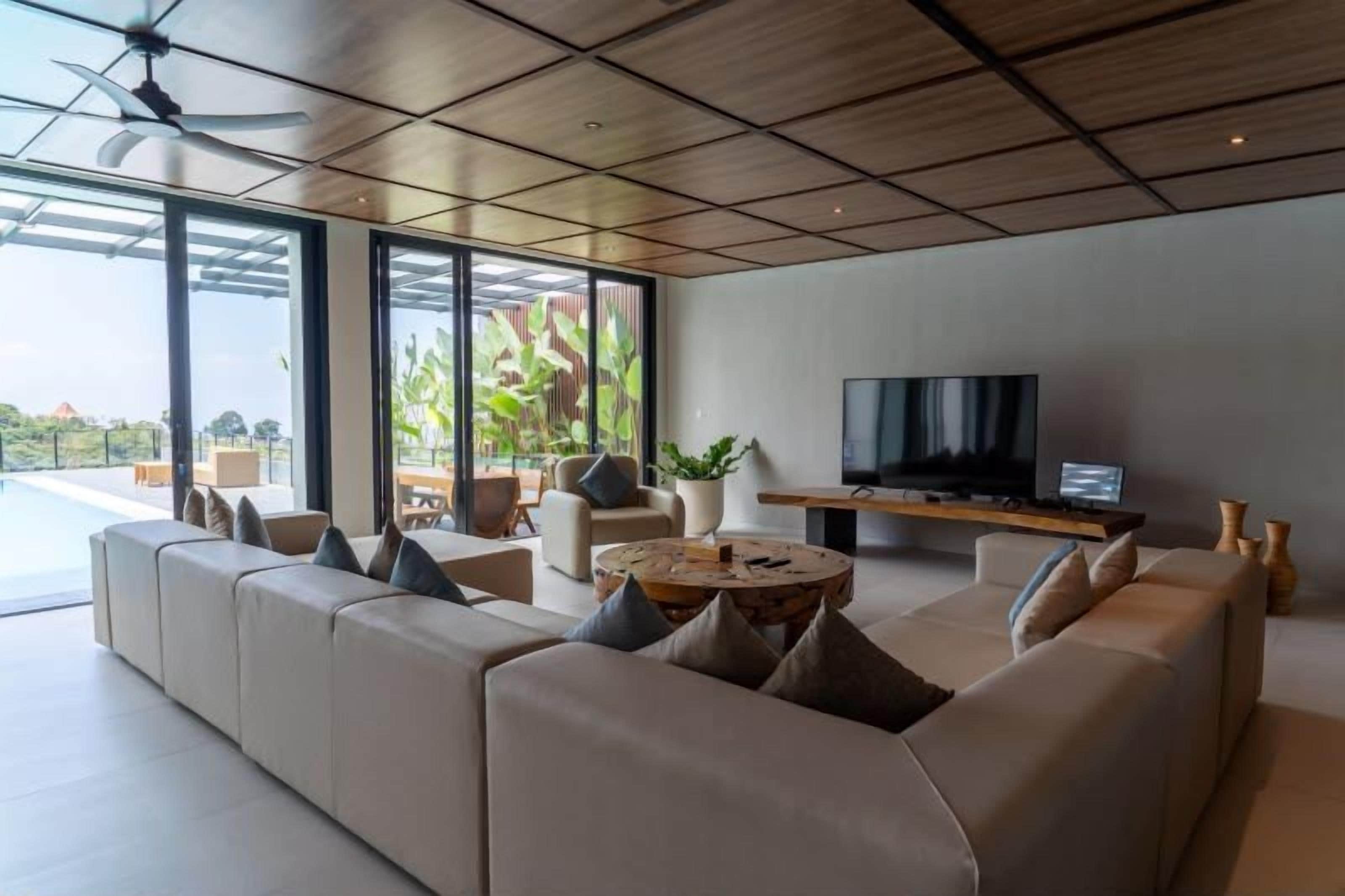 Una sala moderna con un sofá grande, una mesa de centro y una televisión.