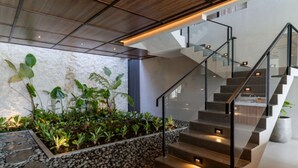 A modern staircase with glass railings, surrounded by a stone wall and lush greenery. - Diamond Hill 10 Br Heated Pool (Bandung)