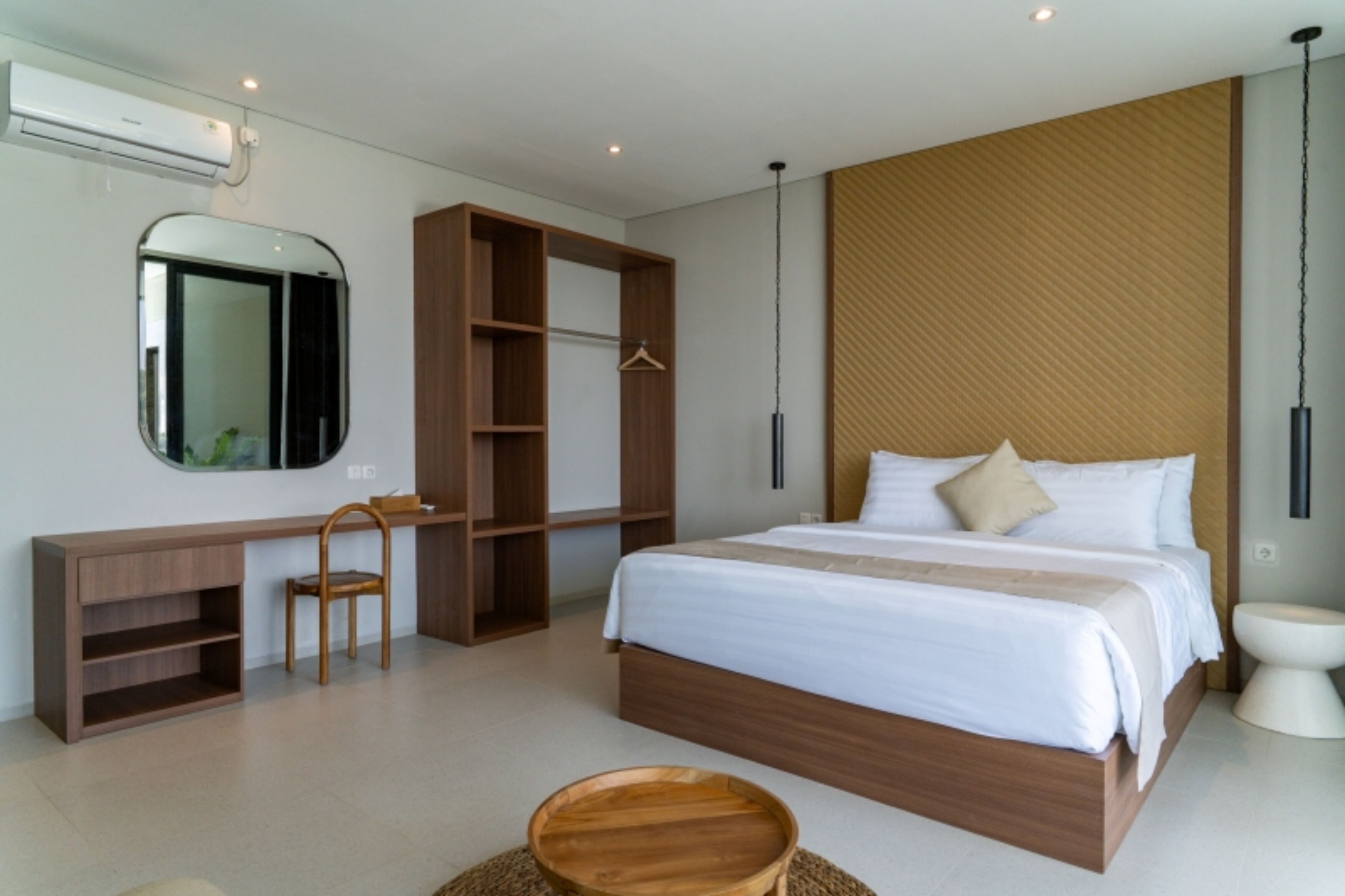 Een moderne slaapkamer met een bed, een bureau, een stoel, een hanglamp en een toilet.