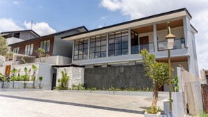 A modern two-story house with large windows, a balcony, and a paved driveway. - Diamond Hill 10 Br Heated Pool (Bandung)