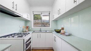 Une cuisine moderne avec des armoires blanches, une cuisinière à gaz et une fenêtre donnant sur l’extérieur.