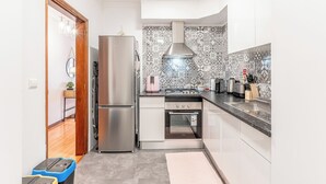 Eine moderne Küche mit Edelstahlgeräten, einer gemusterten Spritzschutzwand und einer Holztür zu einem anderen Raum.