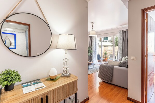 A reception area with a wooden desk, a round mirror, a lamp, a welcome sign, and a potted plant.