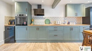 A modern kitchen with light blue cabinets, a built-in oven, and a wooden countertop. - Cheadle Cottage - Hot Tub and Pool Table! (Alton Towers & Staffordshire Villages)