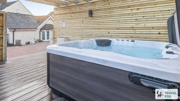 A hot tub under a wooden pergola with a view of a house in the background. - Cheadle Cottage - Hot Tub and Pool Table! (Alton Towers & Staffordshire Villages)